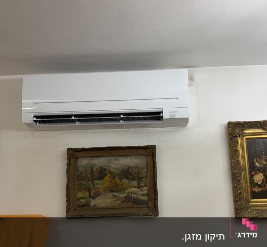 מזגן מותקן על קיר עם תמונות ממוסגרות